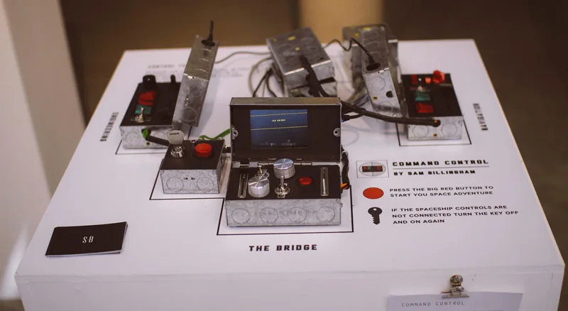Command Control installation with three handmade control boxes, phone displays, switches, dials, and a large start button